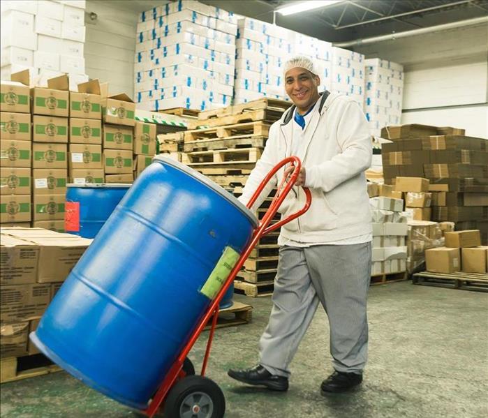 A man carts around a barrel in a factory